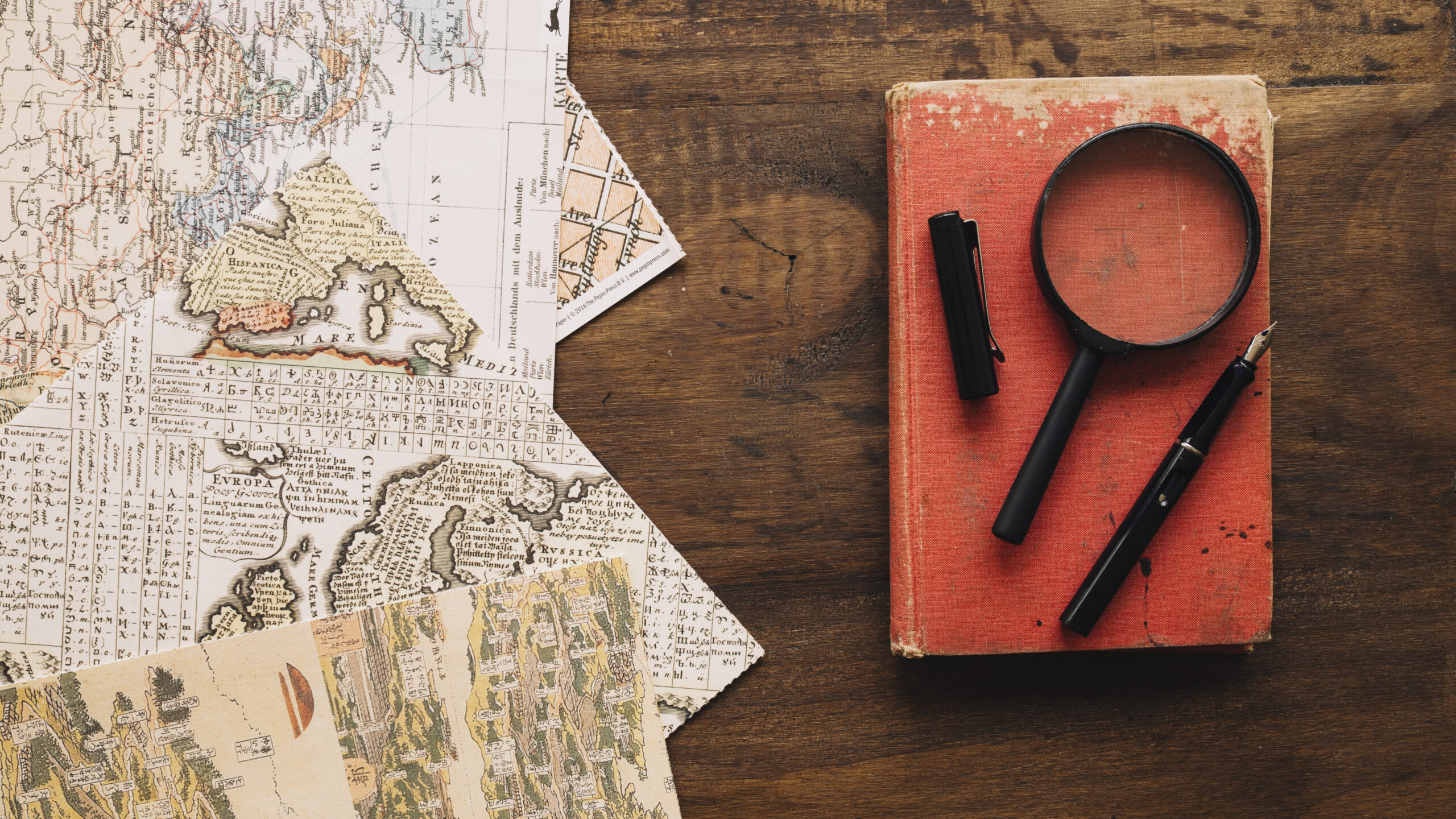 Book magnifying glass near maps