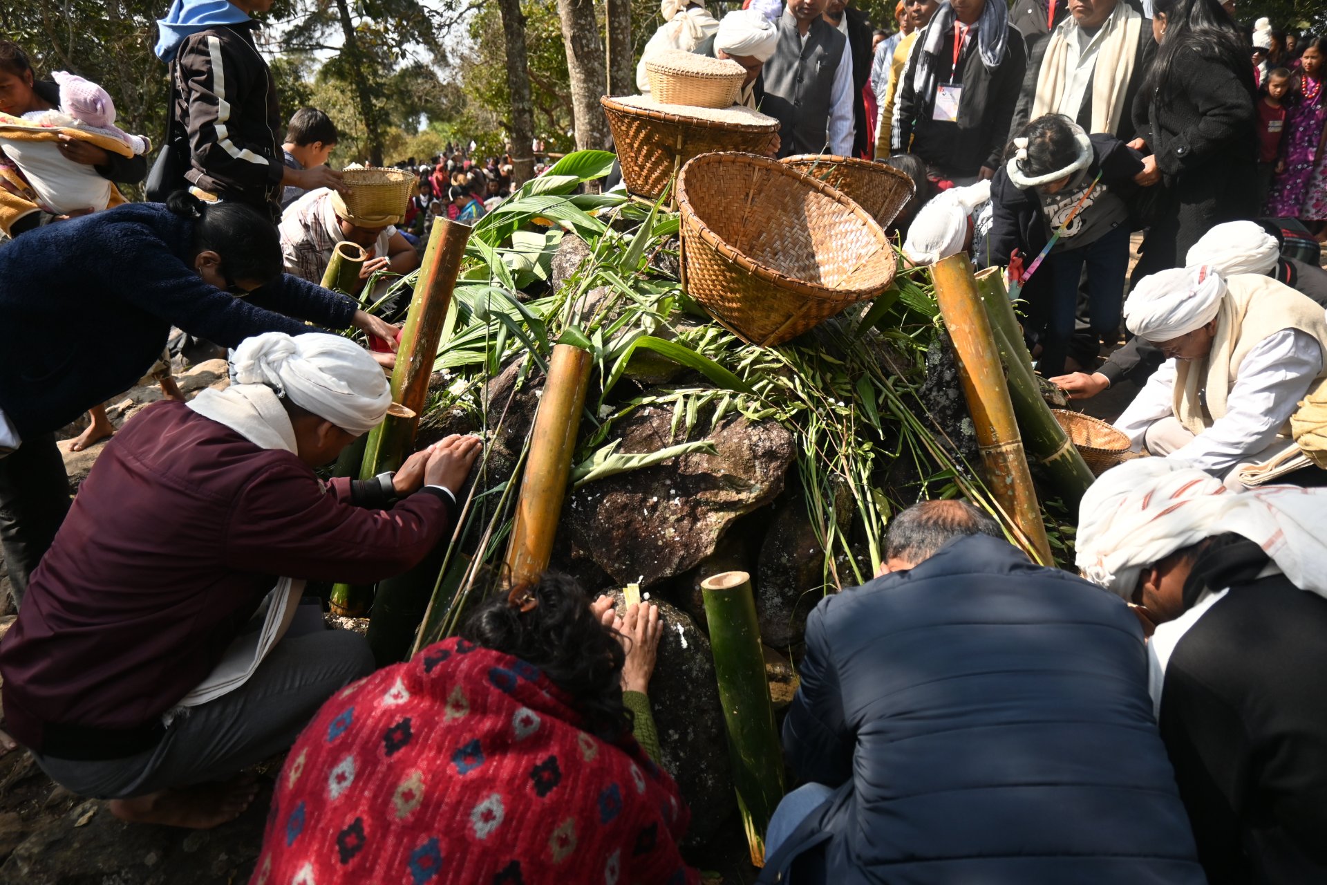 Pilgrims performing a ritual around a stone cairn with bamboo and baskets at Lum Sohpetbneng, Meghalaya