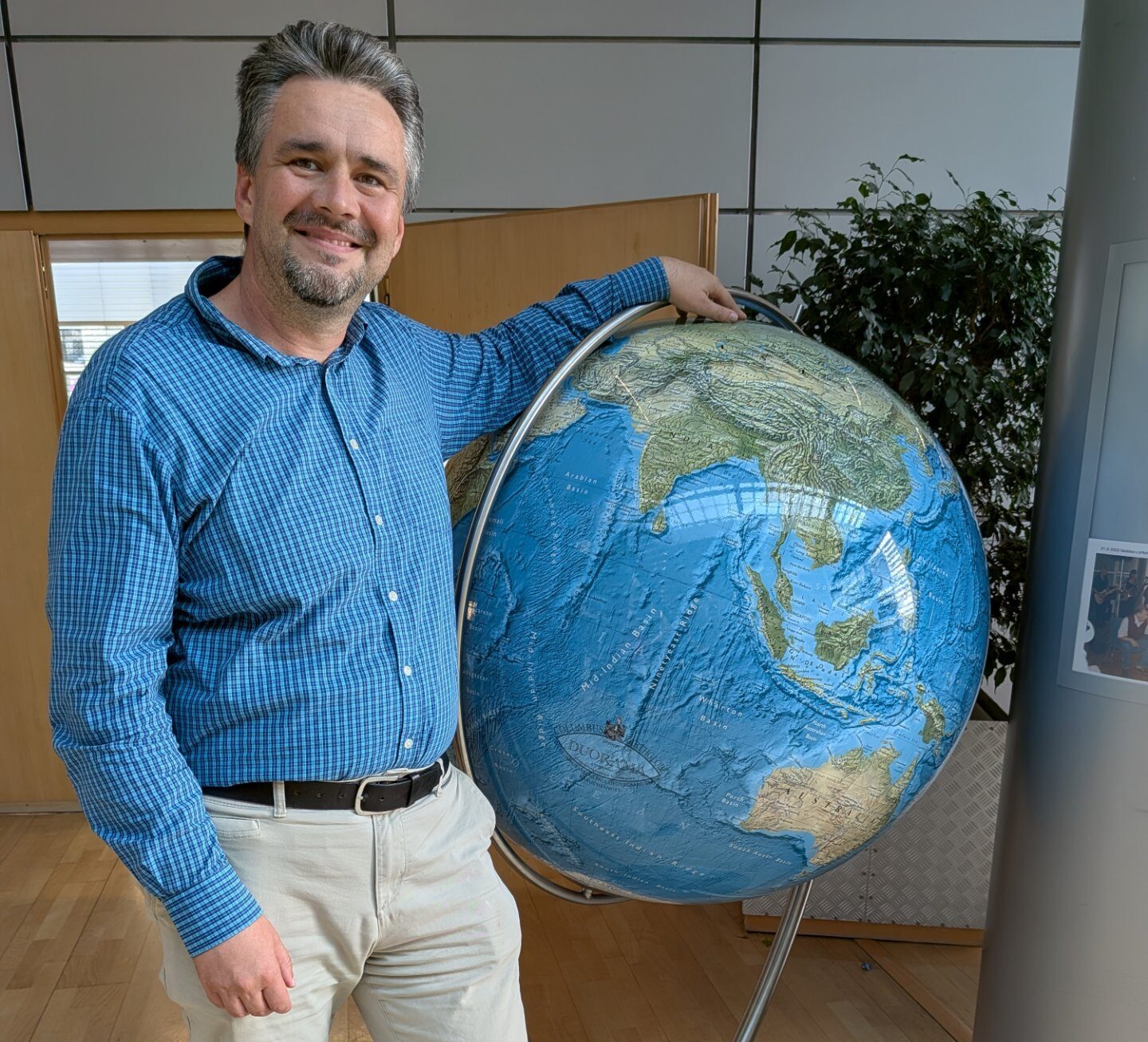 Emil Drápela standing next to a large globe
